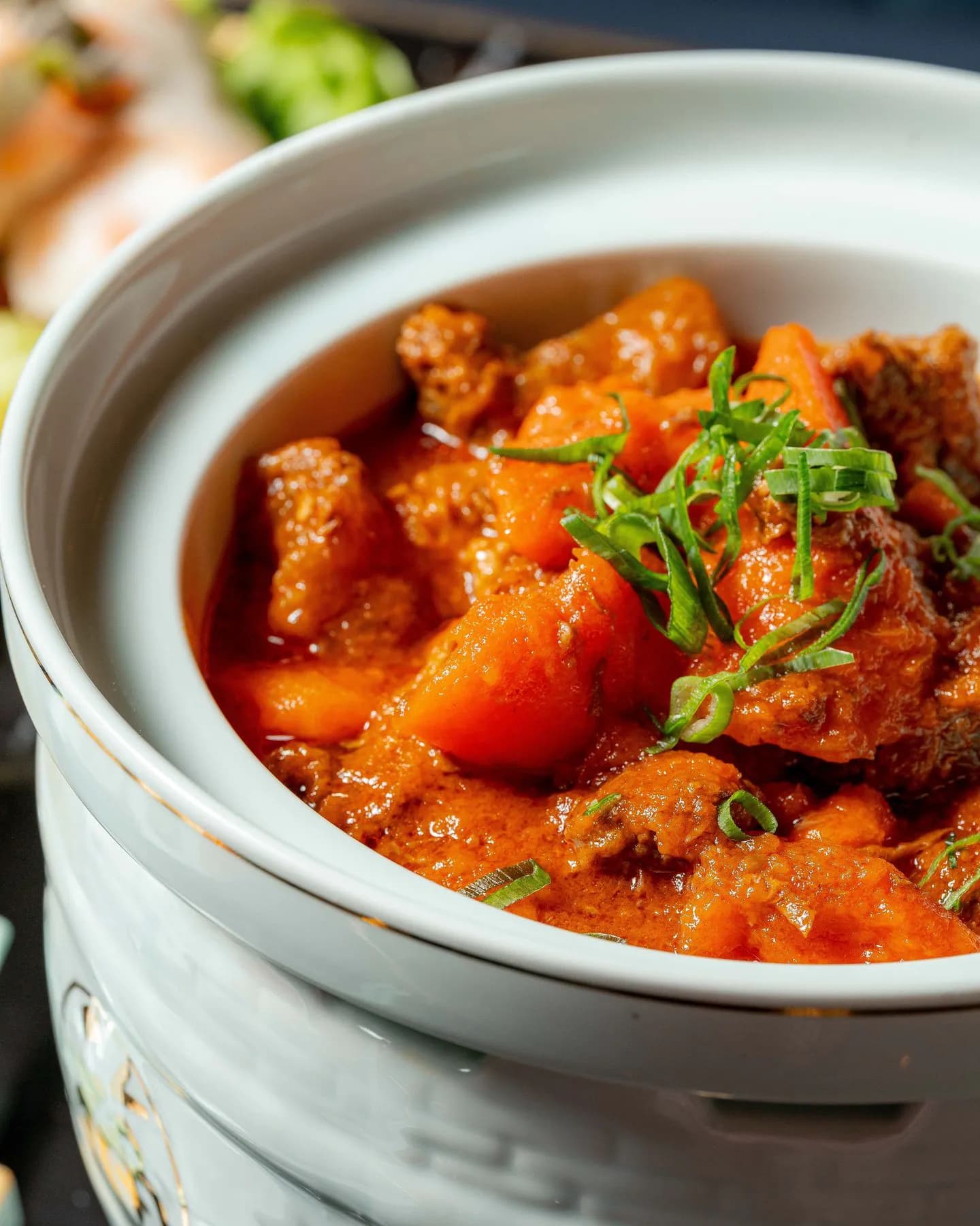 Bol de phở vietnamien fumant dressé sur marbre noir avec herbes fraîches