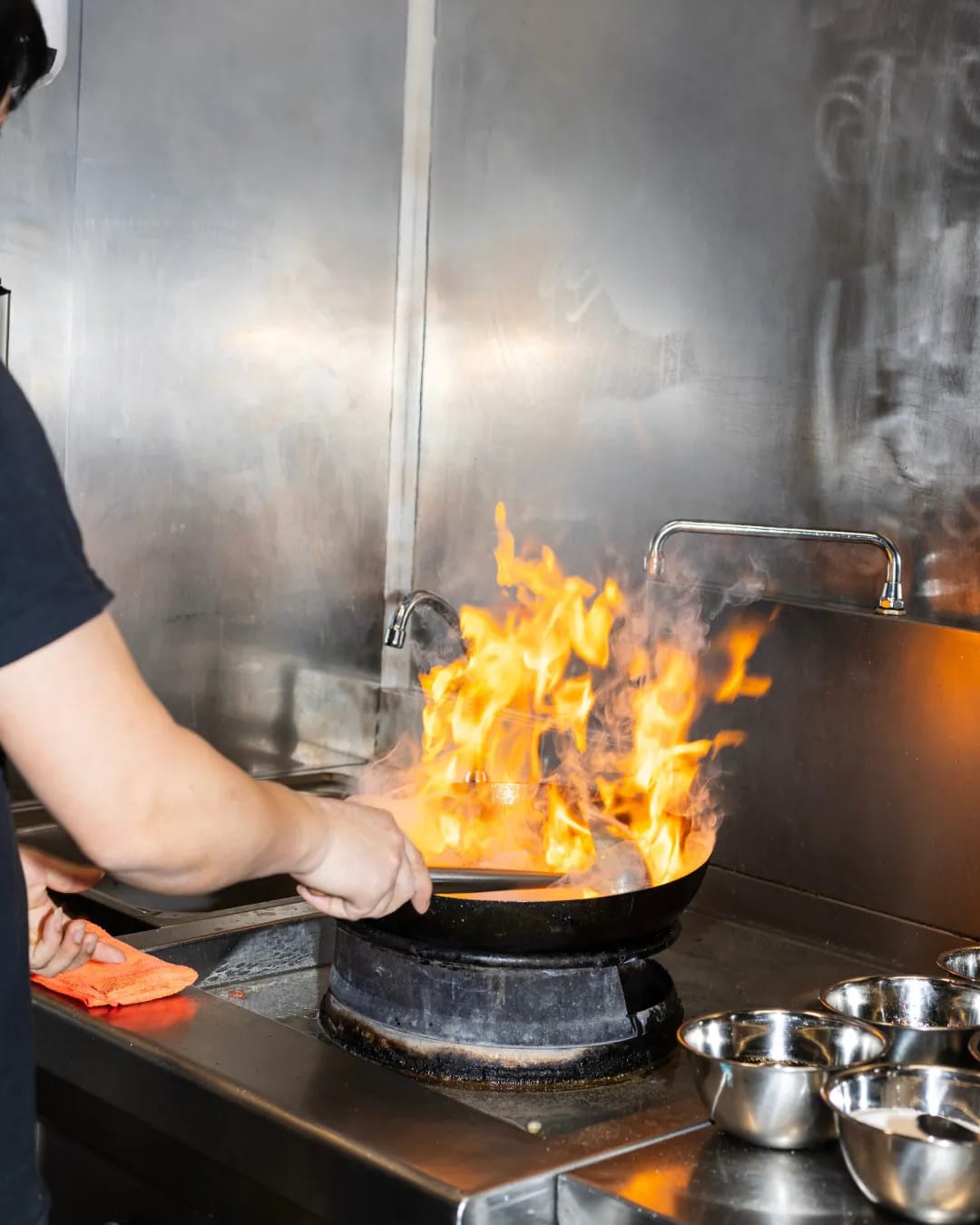 Wok in action in the Phở 98 kitchen, rising flame above the live fire