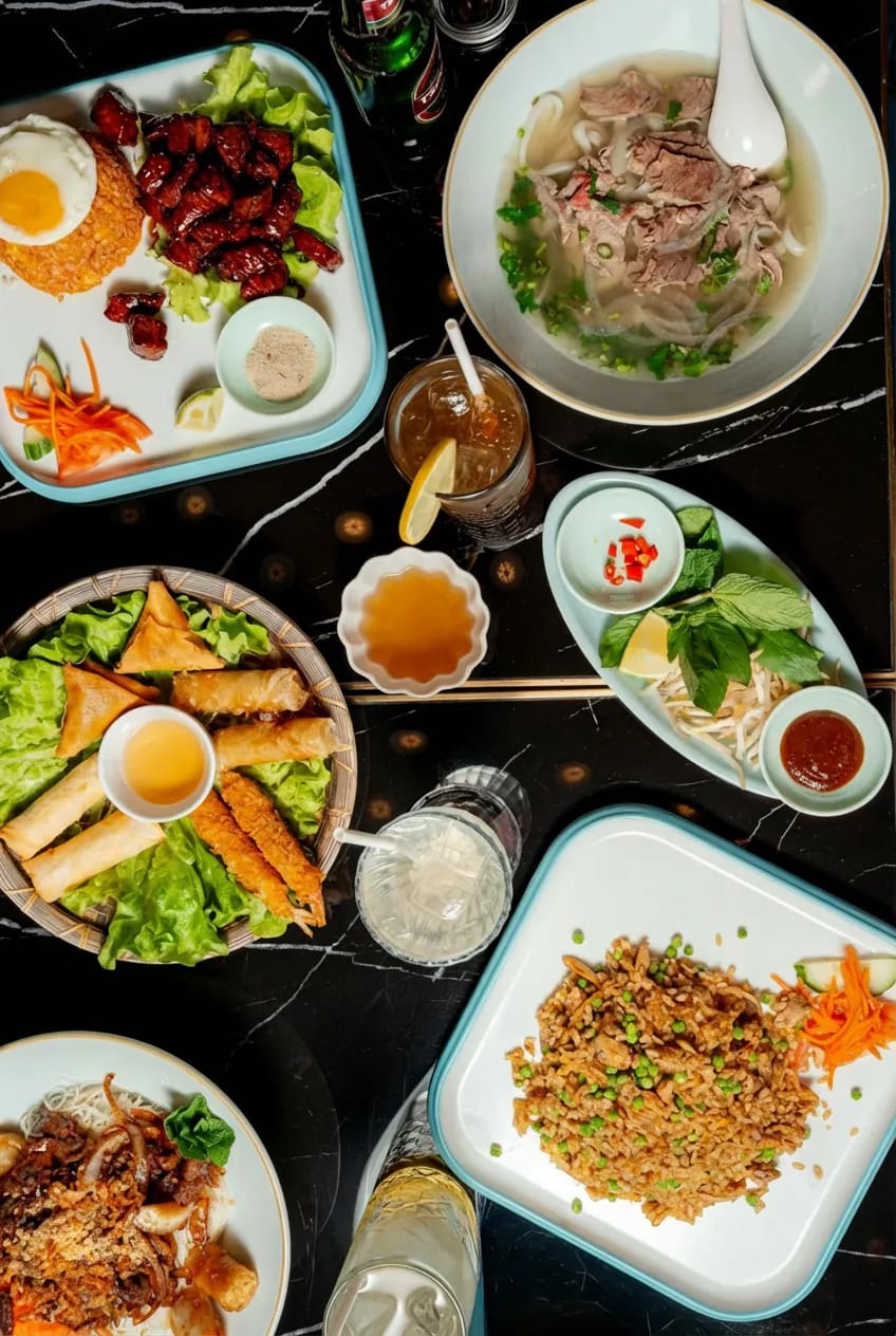 Table set with spring rolls, phở and sides